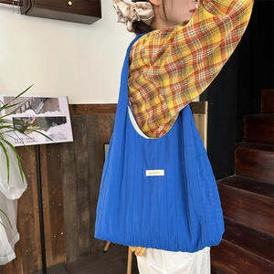Detail view of the bright blue pleated fabric tote bag with a white brand label