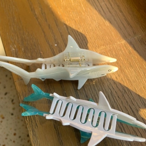 Detailed close-up of whale-shaped acetate hair claws in white and blue gradient colors
