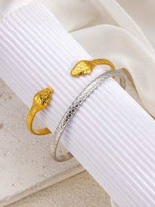 Close-up of snake-shaped open bracelets with golden finish and detailed scale texture