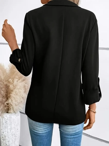 Detailed view of women's black blazer sleeves featuring stylish golden buttons decoration