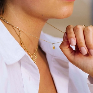 Golden necklace with rectangular yellow gemstone pendant styled in layered fashion