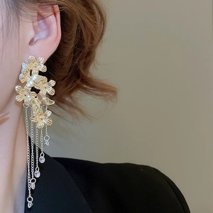 Macro shot of gold floral butterfly long tassel earrings with crystal fringe details