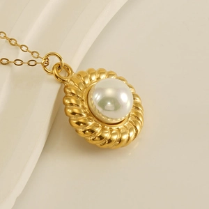Macro shot of 18k gold-plated pendant with a single white pearl and radiating texture