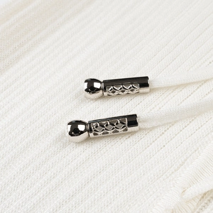 Detail of white knit fabric with drawstring and hollow silver metal decorative tips