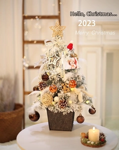 Close-up of a decorated mini Christmas tree with gold star, pine cones, and warm lights