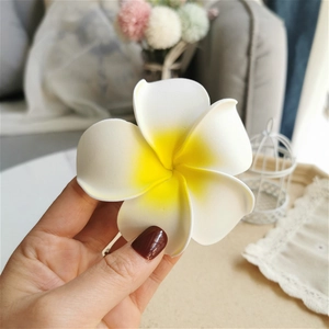 Close-up of a realistic white and yellow EVA foam plumeria flower hair clip