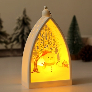 Close-up of a white Christmas lantern featuring a snowman scene and warm interior light