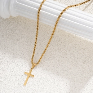 Detail of golden cross pendant on a rope chain displayed on a white marble pillar
