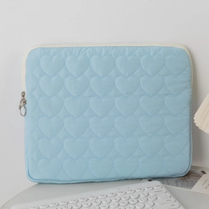 Macro detail of sky blue quilted laptop sleeve with embossed heart patterns and zipper