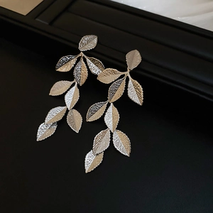 Macro view of metallic leaf tassel earrings with detailed texture and silver finish