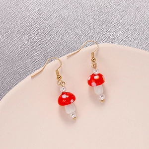 Vue détaillée des boucles d'oreilles champignons en céramique avec perles et crochet doré