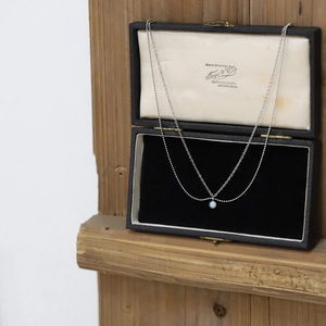 Double layer silver necklace with iridescent opal pendant in a vintage jewelry box