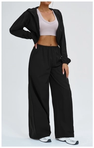 Detail view of black hooded jacket, lavender sports bra and high-waisted wide-leg pants