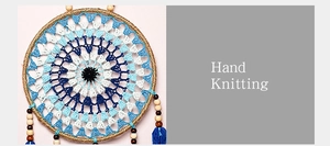 Close-up of hand-knitted bohemian evil eye dreamcatcher with blue feathers and wood beads