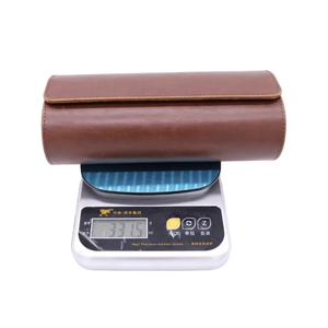 Brown PU leather watch roll travel case displayed on a digital scale weighing 331.5g
