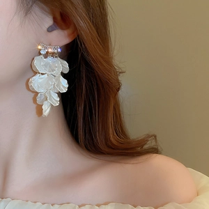 Détail de boucles d'oreilles à fleurs blanches et glands portées par un mannequin