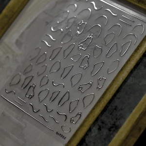 Macro detail of silver mirror laser nail art stickers with French lines and wave patterns