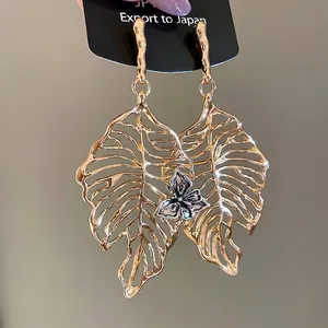Elegant gold leaf earrings with intricate silver floral detail and textured drop design