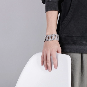Macro view of wide D-shaped silver cuban chain bracelet on male model wrist