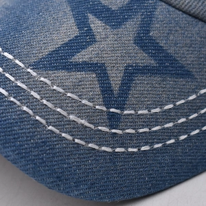 Detail of blue denim baseball cap brim featuring embroidered stars and white stitching