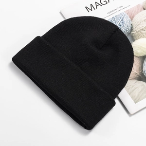 Detailed top view of a classic black knit beanie on a fashion magazine background