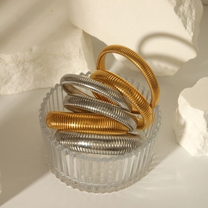 Detail of gold and silver textured spring bracelets on a white stone background