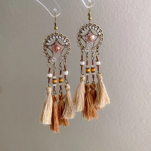 Detail of vintage ethnic earrings featuring pink floral charms and layered feather tassels