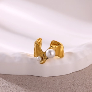 Irregular gold molten metal open ring with two white pearls on a textured pedestal