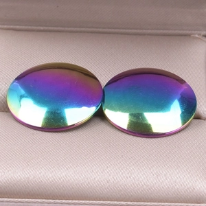 Macro shot of iridescent rainbow stainless steel round ear studs in a jewelry box