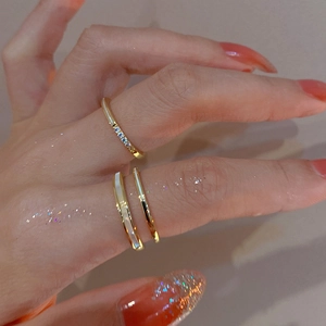 Detail of gold-plated double-layer stackable rings with zircons and white enamel