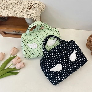 Detailed view of polka dot cosmetic bags with 3D wing accents in green and black