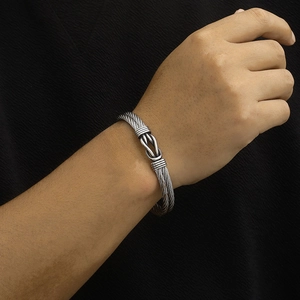 Close-up of twisted steel cable bracelet with knot design on a male model's wrist