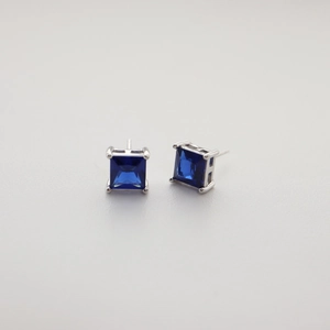 Macro shot of blue square zircon stud earrings with silver four-prong setting details