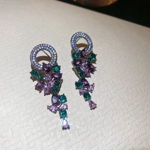 Macro shot of silver stud earrings with zircon tassels and colorful drop-shaped gemstones