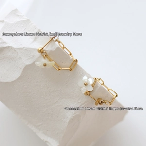 Detailed view of 18K gold plated chain earrings with white mother of pearl flower charms