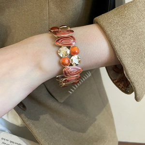 Detail view of vintage gold-tone bracelet with orange enamel inserts and spiral patterns