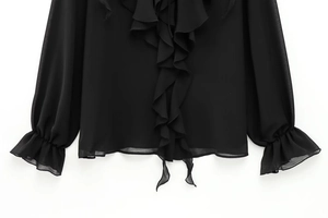 Detailaufnahme der schwarzen Bluse mit Rüschenverzierung und ausgestellten Ärmeln