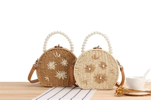 Vue détaillée du sac rond tissé avec poignée en perles et broderie florale élégante