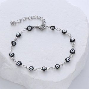 Minimalistisches Armband aus Edelstahl mit Herz-Evil-Eye-Anhängern auf Marmor