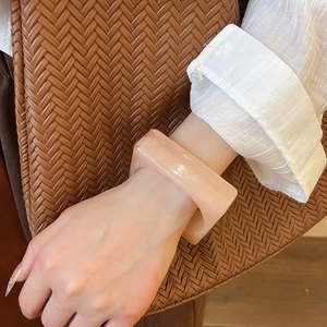 Pink chunky acrylic resin bracelet styled with a linen shirt and woven bag for summer