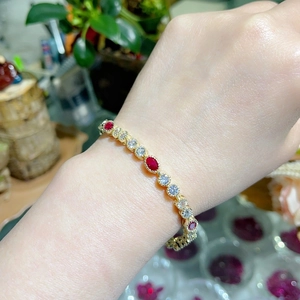 Elegant gold bracelet featuring red rubies and white zircons worn on a female wrist