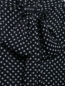 Detailed view of the bow tie neckline on a black and white polka dot chiffon blouse