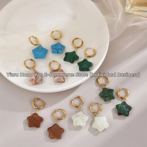 Detailed view of assorted star-shaped natural stone pendants on gold hoop earrings