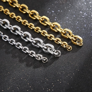 Dettaglio di catene O-link in acciaio inossidabile oro e argento su sfondo nero glitter