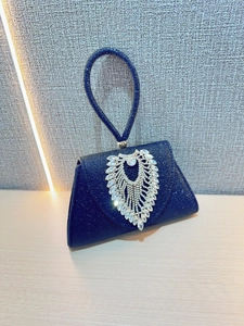 Close-up of sparkling dark blue evening clutch with large crystal leaf embellishment