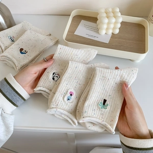 Gros plan sur les broderies d'animaux des chaussettes en coton moucheté blanc