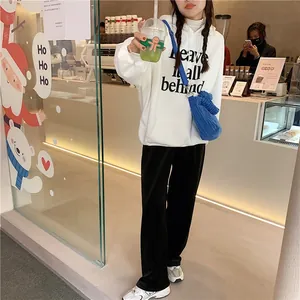 Sac bandoulière en velours bleu porté avec un sweat blanc dans un café douillet