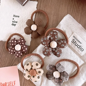 Close-up of five knitted floral hair ties in brown patterns on a wooden surface