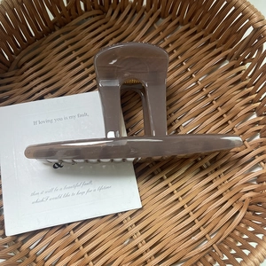 Detail of a square milk tea brown acrylic hair claw clip placed in a woven basket