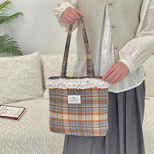 Detail of vintage plaid tote bag featuring delicate white lace trim and Happy fabric label